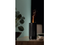 Black aroma diffuser with flame effect on a wooden table with plants.