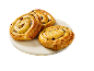 Three golden-brown raisin swirls on a white marble plate