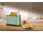 Green toaster with two slices of toast, jam, and a plate of toast on a wooden table.