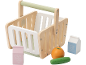 Wooden shopping basket with toy food: milk, grape juice, orange, and cucumber.