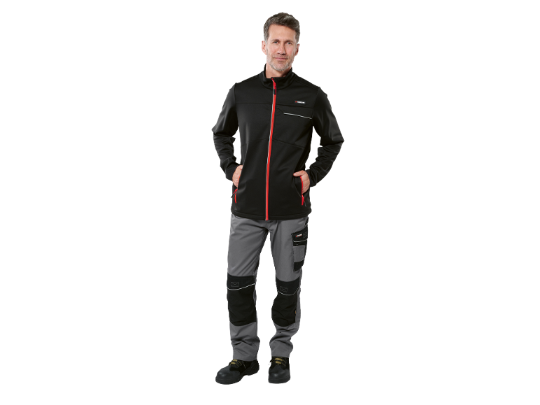 Man in black softshell jacket and grey work trousers with black details.