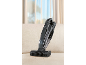 Black cordless handheld vacuum cleaner on a beige sofa, with crumbs and curtains in the background.