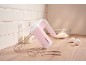 Pink hand mixer with whisks, a bowl of flour, eggs, and milk on a wooden surface.
