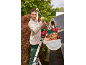 Woman cleaning a gutter with a telescopic brush, standing on a ladder.