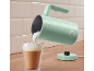 Mint-colored milk frother pouring foam into a glass of coffee.