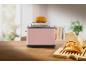 Pink toaster with a bun on top and buns on a wooden cutting board.