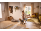 Woman prepares dog for walk, holding leash, in cozy hallway with wooden furniture.