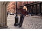 Woman in a knit cardigan and leather trousers on a cobblestone street.