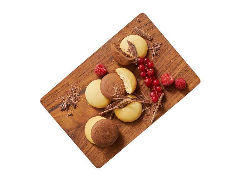 Butter and chocolate cookies with redcurrants and raspberries on a wooden board.