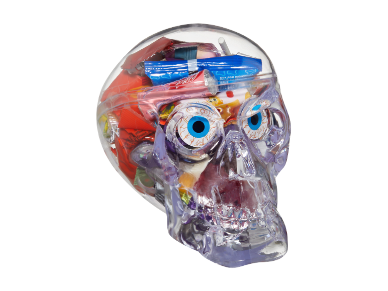 Clear skull filled with assorted Halloween candy, including gummy eyeballs and wrapped sweets.