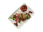 Sliced steak with sun-dried tomatoes and green leaves on a rectangular platter.