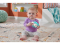 Baby sitting on a rug, holding a hedgehog rattle.