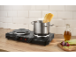 Double electric hot plate with a pot of boiling pasta and fresh ingredients in a kitchen.