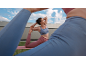 Woman in a sports top and leggings doing yoga on a mat outdoors.