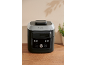 Black and silver multi-cooker with various cooking functions on a wooden surface.
