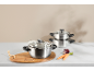 Stainless steel pot set with vegetables on a kitchen counter.