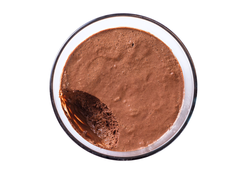 Chocolate mousse in a glass bowl with a missing scoop, top view.