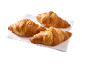 Three golden-brown croissants on a white napkin, ready to be enjoyed.