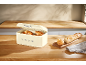 Cream-colored bread bin with croissants and baguettes in a wooden kitchen.