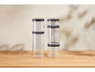 Stackable clear food containers with black lids on a wooden table.