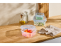 Plastic food containers, oil bottles, and a pitcher on a wooden table.