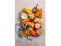 Snack board with hummus, carrots, crackers, nuts, and fruit