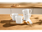 White ceramic mugs on a wooden kitchen counter with cookies in the background.