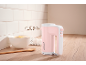 Pink and white hand mixer with beaters, bowl of flour, eggs, and wooden spoon on a kitchen counter.