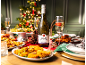 Prosecco bottle and glasses with Christmas party food and an illuminated Christmas tree.