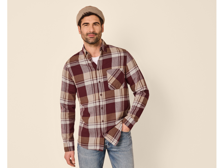 Man in plaid flannel shirt, white t-shirt, and jeans with a beanie.