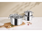 Stainless steel pot set with glass lids, garlic, rosemary, and mushrooms.