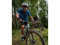 Two cyclists on mountain bikes riding on a forest trail.