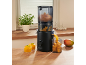 Black slow juicer with mango pieces making mango puree in a kitchen.