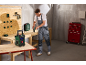 Man in work overalls drilling wood, with a radio and tool case nearby.