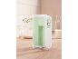 Green and white electric hand mixer on a wooden kitchen counter with baking ingredients.
