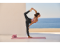 Woman in leggings and sports bra doing yoga on a mat with blocks.