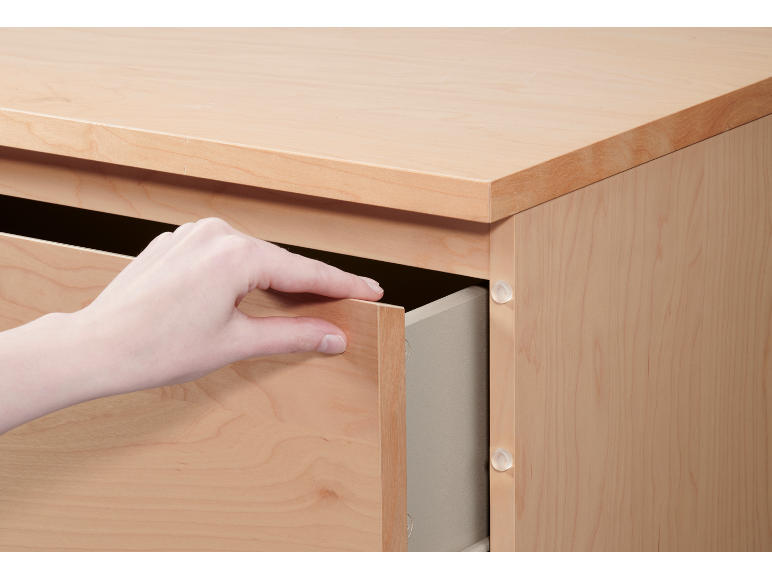 Hand opening a light wooden drawer in a wooden cabinet.