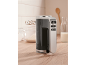 Black and silver hand mixer with kitchen accessories on a wooden countertop.