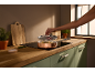 Cooking in a copper pan on an induction hob, with a wooden cutting board and herbs.
