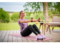 Woman in purple t-shirt and black leggings exercising with dumbbells on a yoga mat.