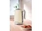 Cream-colored kettle with '1973' text on a wooden countertop with cookies.