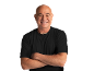 Smiling bald man in a black t-shirt and necklace, with arms crossed.