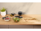 Glass bowls with lids, salad, berries, and olives on a wooden countertop.