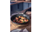 Meat wrapped in bacon and sage in a frying pan on a wooden table.