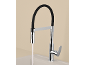 Modern kitchen faucet with a black flexible hose and running water into a sink.