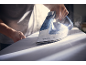 Person ironing white fabric with a steam iron emitting steam.