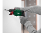 Green and black hammer drill being used to drill into a white wall.