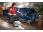 Woman cleaning blue sofa with a carpet and upholstery cleaner.