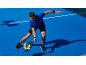 Man in sportswear playing padel on a blue court.
