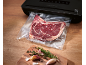 Vacuum-sealed beef steak with herbs and garlic on a wooden table.